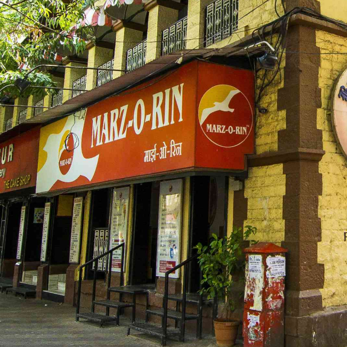The iconic red-brick heritage building of Marz-O-Rin on MG Road, Pune, with its distinctive green balconies.